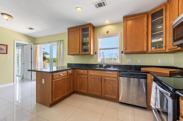 kitchen with brown cabinets, dark countertops, recessed lighting, appliances with stainless steel finishes, and light tile patterned floors