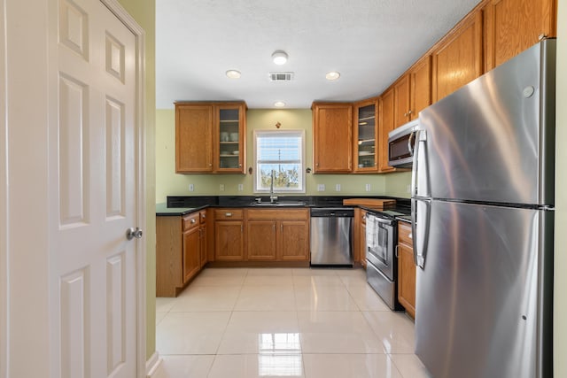 kitchen featuring brown cabinetry, visible vents, appliances with stainless steel finishes, and a sink