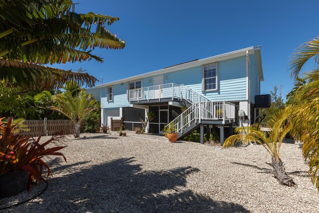 back of house featuring stairway, central air condition unit, a sunroom, and fence