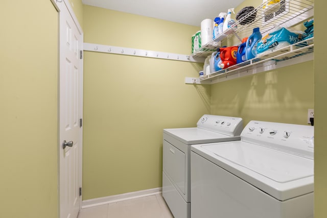 washroom featuring light tile patterned floors, laundry area, washing machine and dryer, and baseboards