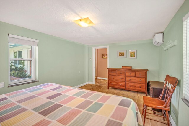 bedroom with light tile patterned floors, an AC wall unit, and a textured ceiling