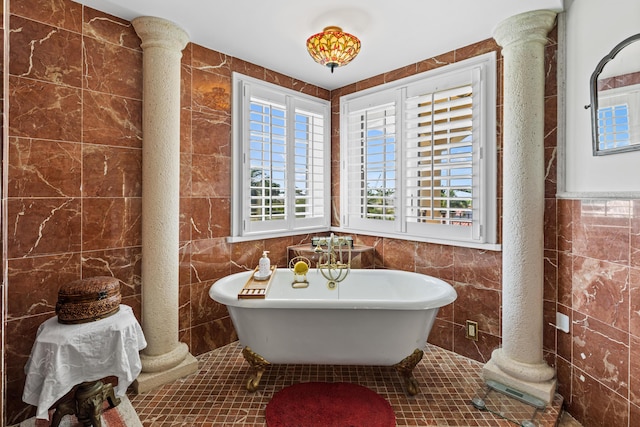 bathroom featuring plenty of natural light, a bath, tile walls, and ornate columns