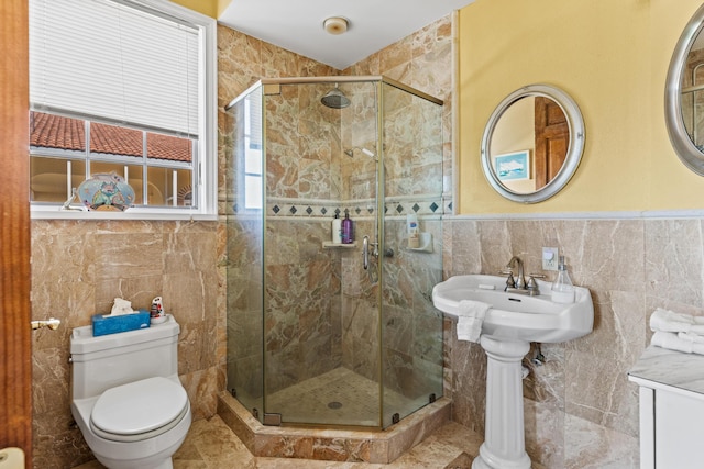 bathroom featuring toilet, a shower with shower door, and tile walls