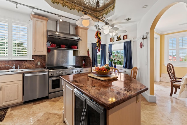 kitchen with sink, a kitchen island, stainless steel appliances, beverage cooler, and decorative backsplash