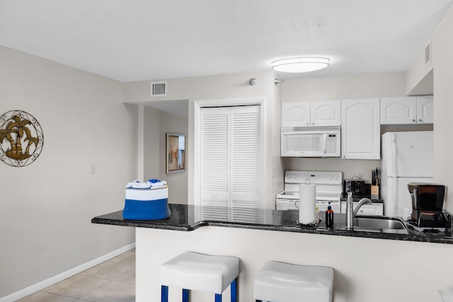 kitchen with sink, a kitchen breakfast bar, kitchen peninsula, white appliances, and white cabinets