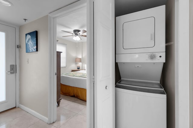 washroom featuring stacked washer and dryer, light tile patterned floors, and ceiling fan