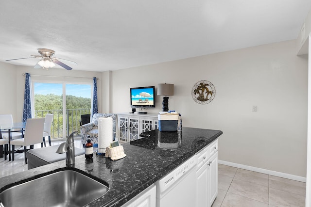 kitchen featuring light tile patterned flooring, sink, white cabinets, dark stone counters, and white dishwasher