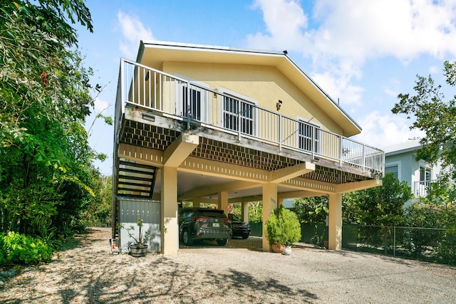 view of front of house with a carport, driveway, stucco siding, and fence