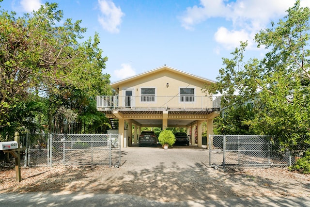 coastal home with a carport, a gate, fence, and dirt driveway