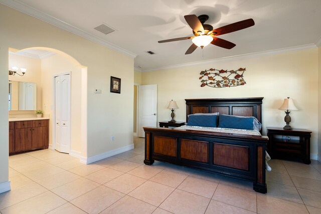 bedroom featuring ornamental molding, ensuite bath, ceiling fan, and light tile patterned floors