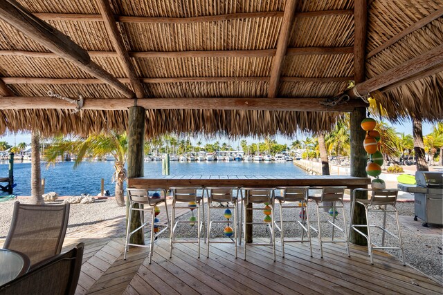 view of dock with a deck with water view, a gazebo, and an outdoor bar