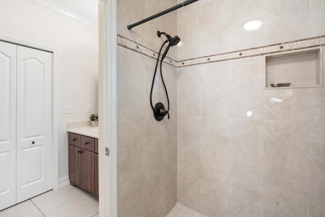 bathroom featuring tiled shower, crown molding, tile patterned flooring, and vanity