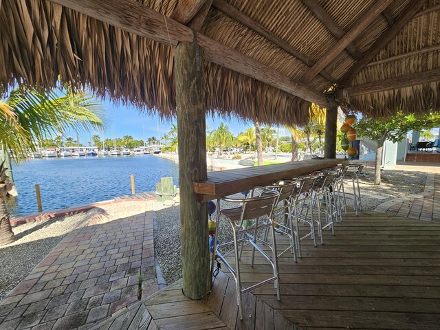 view of dock featuring a water view, a gazebo, and exterior bar