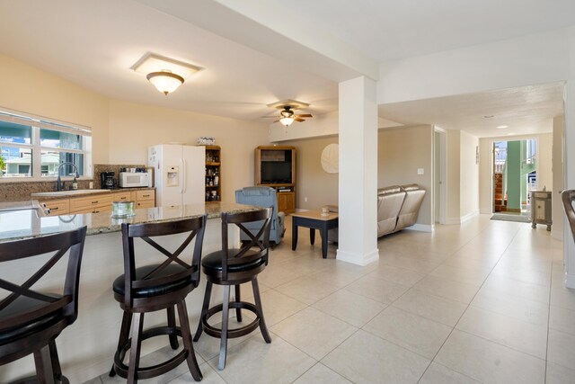 kitchen featuring white appliances, light stone counters, ceiling fan, decorative backsplash, and sink