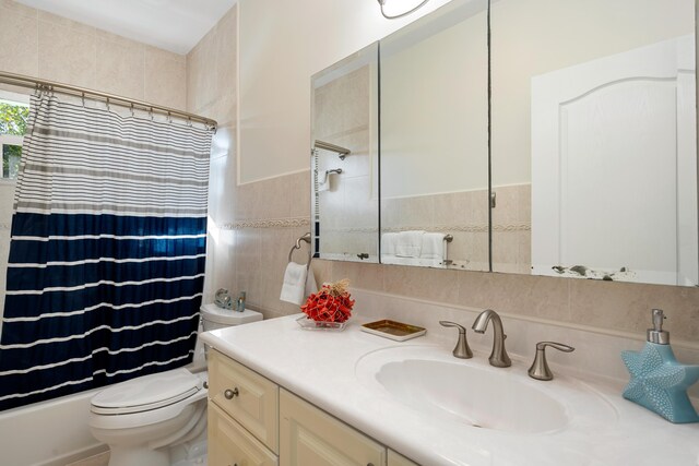 full bathroom featuring tile walls, vanity, toilet, and shower / bath combo