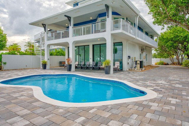 rear view of property featuring a balcony, a fenced in pool, and a patio