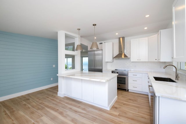 kitchen with decorative light fixtures, white cabinetry, high end appliances, a center island, and wall chimney exhaust hood