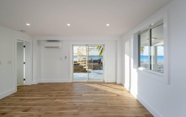 interior space featuring a water view, a wall mounted AC, and light hardwood / wood-style floors