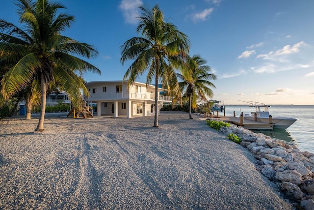 view of front of house with a dock, a balcony, and a water view