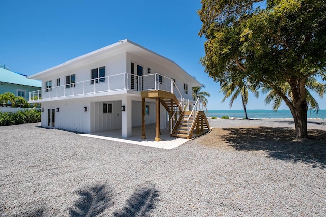 rear view of property with a water view and a beach view