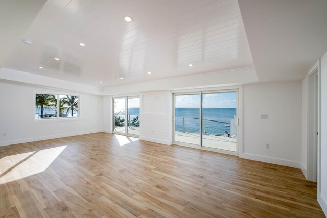 unfurnished living room featuring a water view and light hardwood / wood-style floors