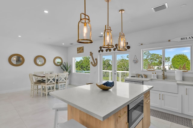 kitchen featuring pendant lighting, sink, white cabinets, a center island, and stainless steel appliances