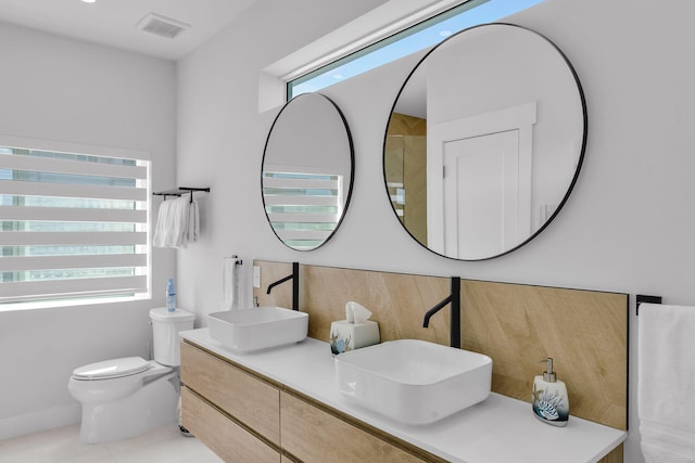 bathroom with tile patterned floors, vanity, toilet, and a wealth of natural light