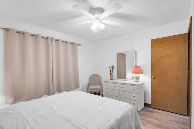 bedroom with ceiling fan, a textured ceiling, and light hardwood / wood-style floors