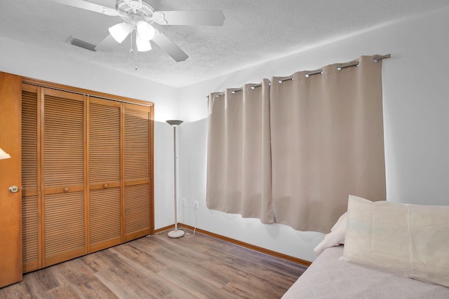 unfurnished bedroom with hardwood / wood-style flooring, a closet, ceiling fan, and a textured ceiling