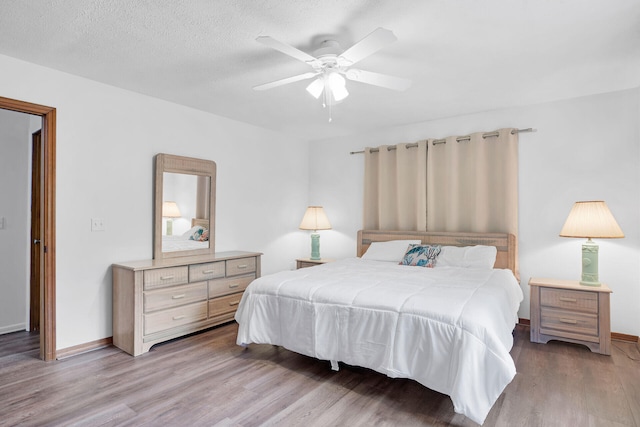 bedroom with ceiling fan, light hardwood / wood-style flooring, and a textured ceiling