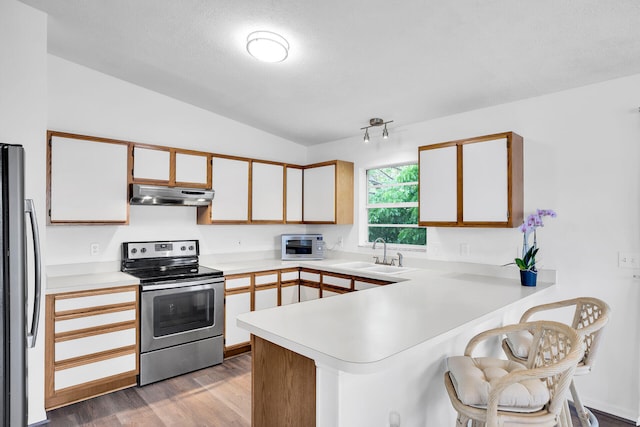 kitchen featuring appliances with stainless steel finishes, white cabinetry, sink, kitchen peninsula, and light hardwood / wood-style flooring