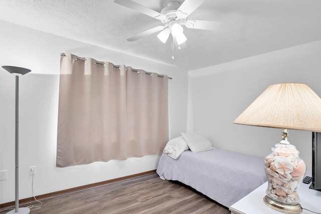 bedroom featuring ceiling fan, hardwood / wood-style floors, and a textured ceiling