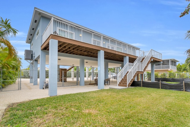 back of house featuring a wooden deck, a yard, and a patio area