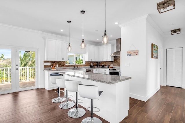 kitchen featuring white cabinetry, a center island, light stone counters, and wall chimney exhaust hood