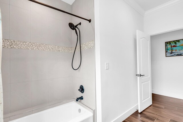 bathroom with hardwood / wood-style flooring, tiled shower / bath, and crown molding