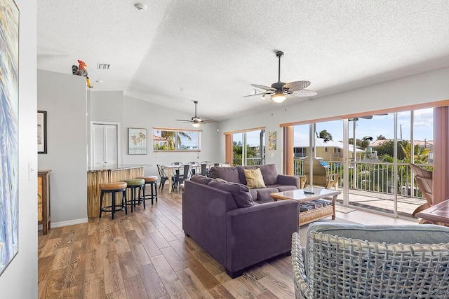 living room featuring dark wood-type flooring, a textured ceiling, and vaulted ceiling