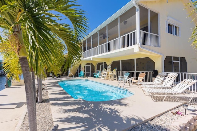 view of swimming pool featuring a patio, a sunroom, and ceiling fan