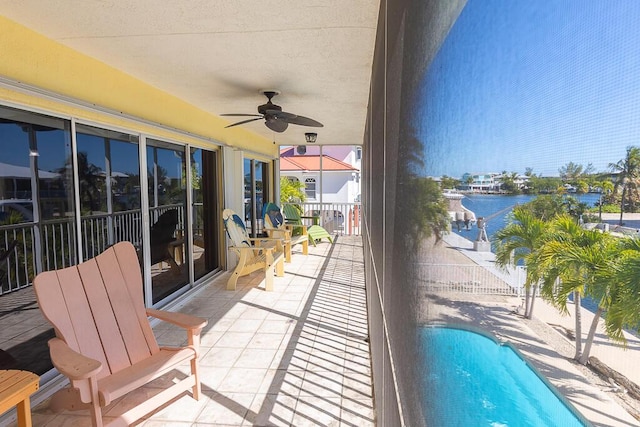 view of patio / terrace with a fenced in pool, ceiling fan, and a water view