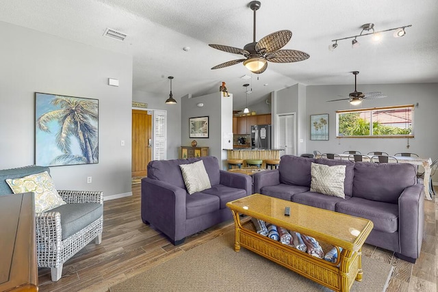 living room featuring lofted ceiling, dark wood-type flooring, a textured ceiling, and ceiling fan