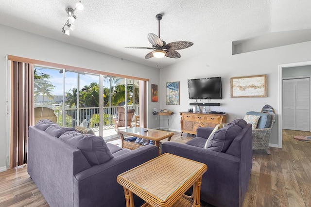 living room with ceiling fan, hardwood / wood-style floors, track lighting, a textured ceiling, and vaulted ceiling