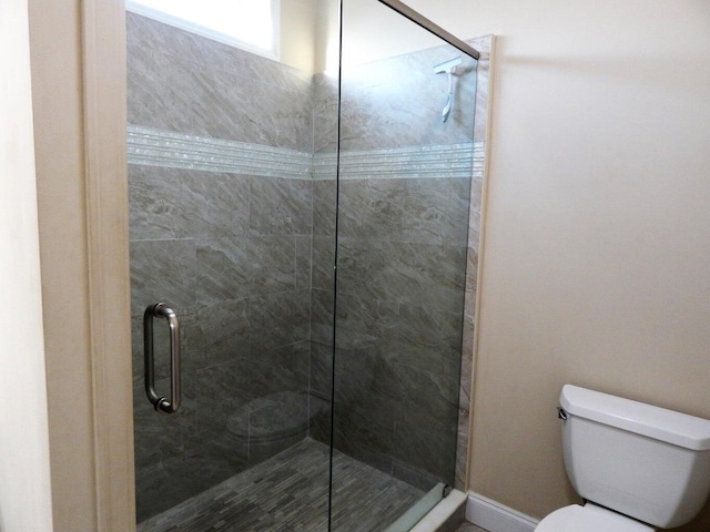 bathroom with a shower with door and toilet