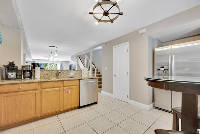 kitchen with sink, light tile patterned floors, kitchen peninsula, stainless steel appliances, and light stone countertops