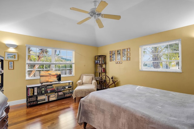 bedroom with lofted ceiling, hardwood / wood-style flooring, multiple windows, and ceiling fan