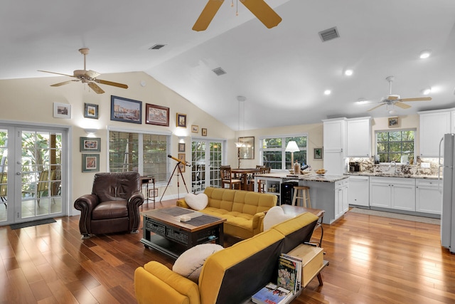 living room with plenty of natural light, light wood-type flooring, and french doors