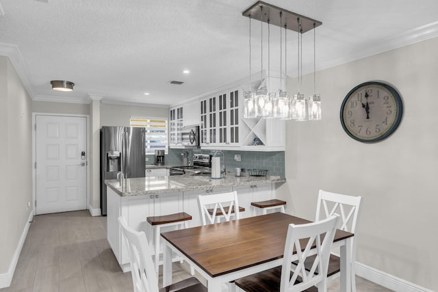 dining area featuring sink, ornamental molding, light hardwood / wood-style floors, and a textured ceiling