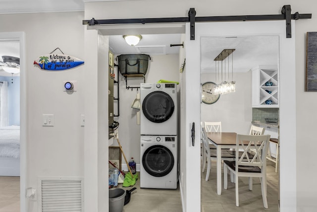 clothes washing area with a barn door and stacked washer and clothes dryer