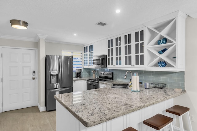 kitchen with sink, white cabinetry, tasteful backsplash, appliances with stainless steel finishes, and kitchen peninsula