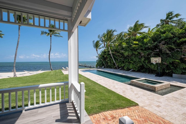 view of swimming pool with an in ground hot tub, a water view, and a yard