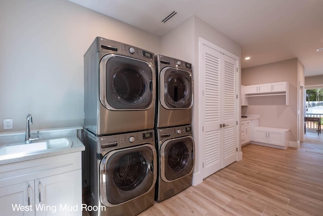 laundry area featuring light wood-style flooring, separate washer and dryer, a sink, stacked washing maching and dryer, and cabinet space