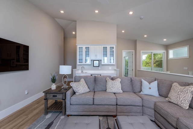 living room with vaulted ceiling, light hardwood / wood-style floors, and sink